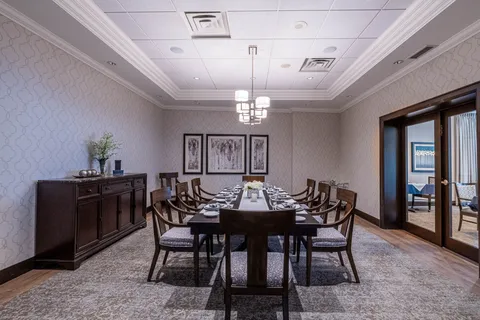 Dining room with a long table, wooden chairs and abstract wall art
