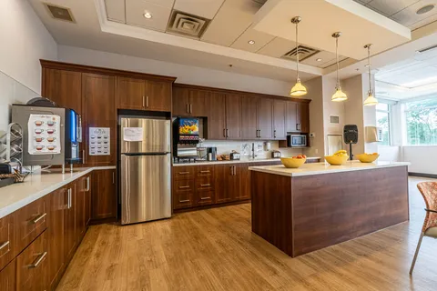 Kitchen with wooden cabinets, a refrigerator, coffee machines and an island