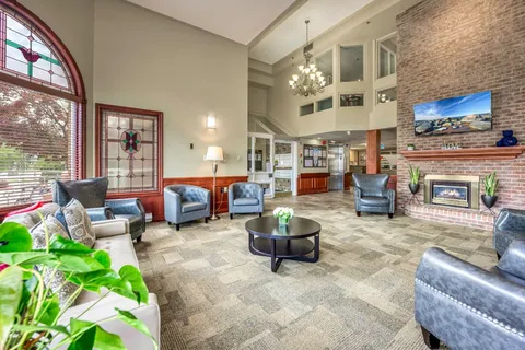 High-ceilinged room with armchairs, a fireplace and a large arched window
