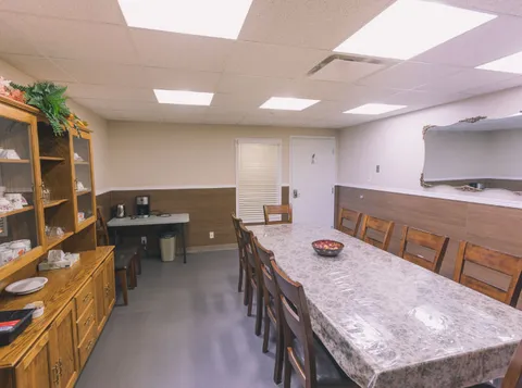 Long table with wooden chairs beside cabinets and a kitchen counter