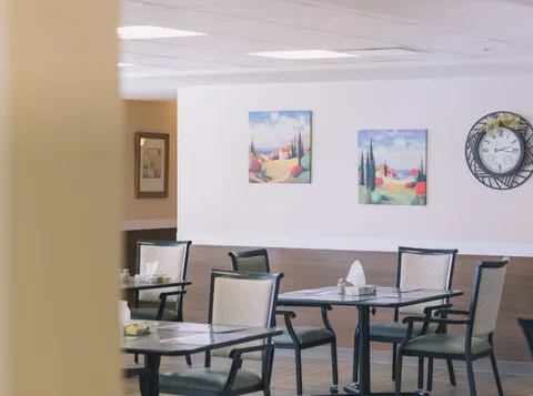 Dining tables and chairs beneath colourful landscape paintings