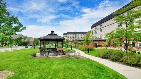 Gazebo beside a lawn, garden paths and residence buildings