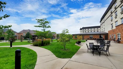 Garden paths and patio seating beside a lawn and planted beds