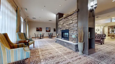 Armchairs beside a double-sided stone fireplace and large windows