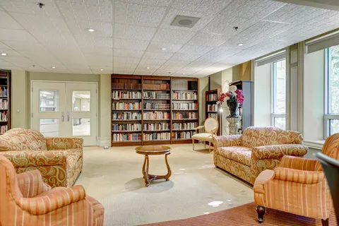 Library with patterned sofas, armchairs, a round table and bookshelves