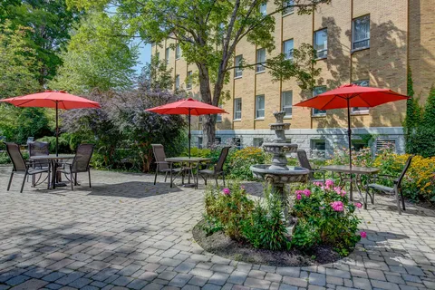 Patio with red umbrellas, metal tables, chairs and a stone fountain