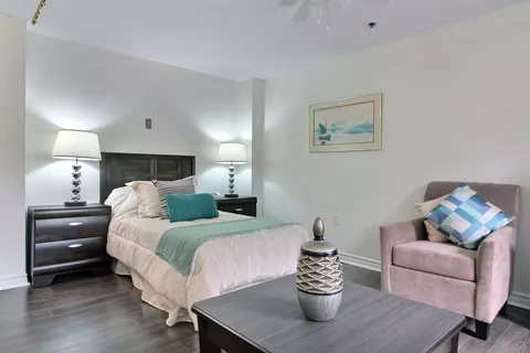 Bedroom with a bed, bedside lamps, an armchair and sailing artwork