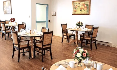 Dining room with set tables, wooden chairs and flower arrangements.