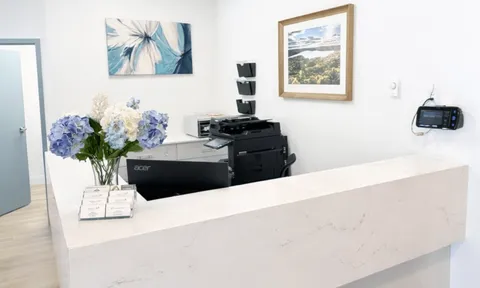 Reception counter with flowers, telephone and framed wall art.