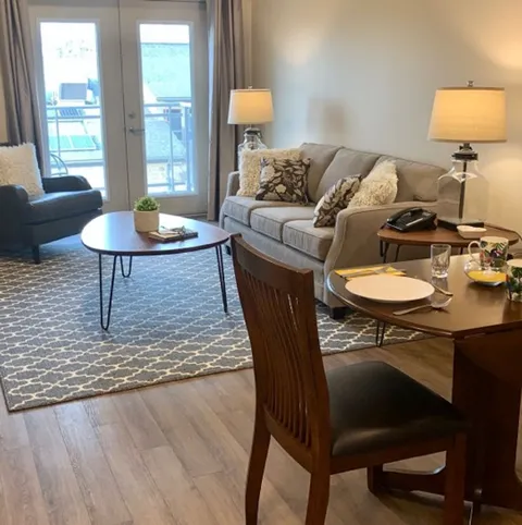 Suite sitting area with a sofa, dining table and balcony door.