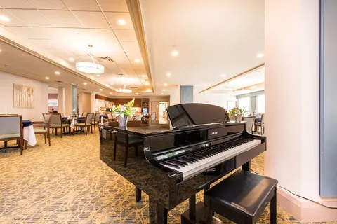 Dining room with a grand piano and upholstered dining chairs.