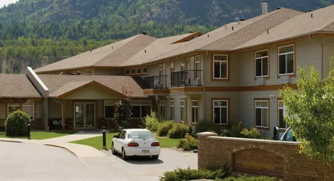 Two-storey residence and covered entrance beside a driveway and planted beds
