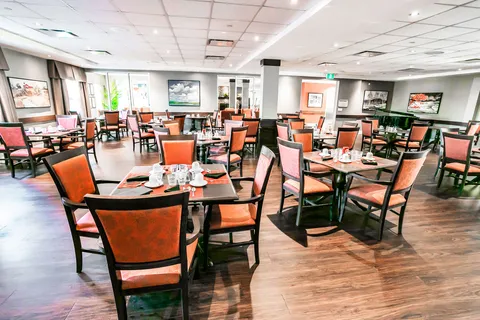 Dining tables set with glasses and orange upholstered chairs