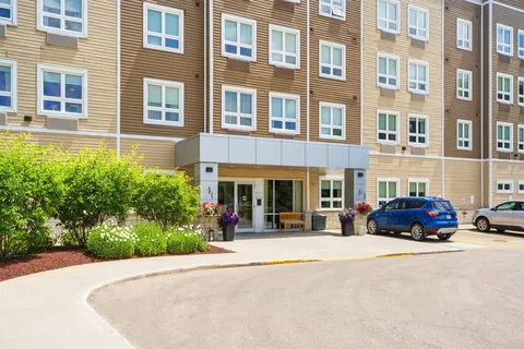 Front of a four-storey building with a sheltered entrance and parked cars