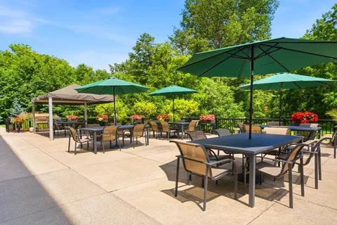 Patio tables and chairs beneath green umbrellas beside a gazebo