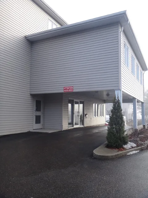 Covered driveway beneath a cream-sided building with an entrance door