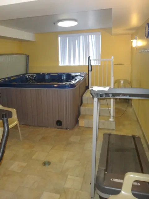 Room with a raised whirlpool tub and an accessible bathing tub