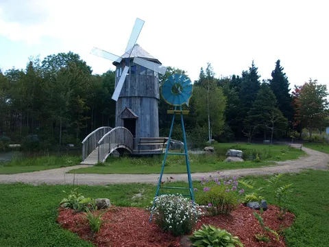 Wooden windmill and small bridge beside garden beds and a path
