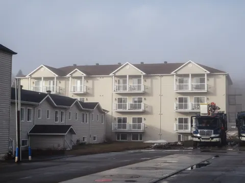 Three-storey cream residence with balconies beside a parked truck