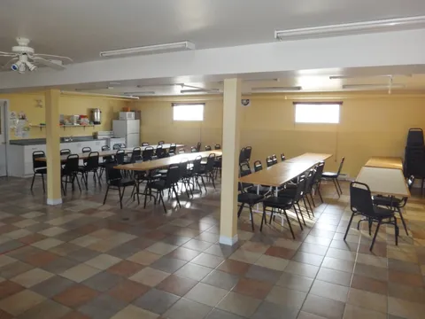 Tables and black chairs in a yellow room with a tiled floor