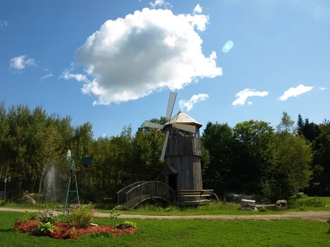 Garden with a wooden windmill, arched bridge, lawn and flower beds