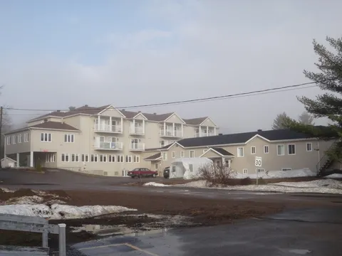 Cream residence with balconies, adjacent buildings and a driveway