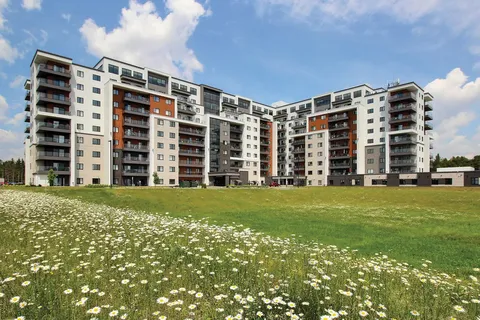 Residence building with balconies behind a lawn with white flowers