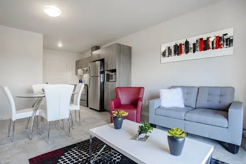 Sofa, red armchair and dining table beside a kitchenette