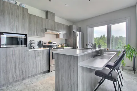 Kitchen with gray cabinets, appliances and a breakfast counter