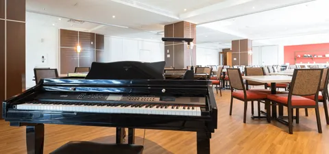 Grand piano beside dining tables and chairs in a bright room