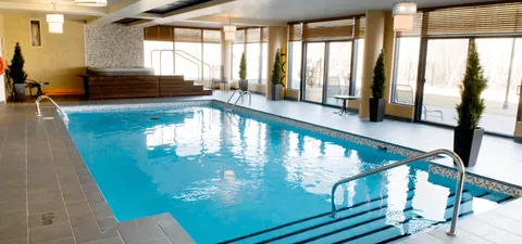 Indoor swimming pool with handrails and tall windows