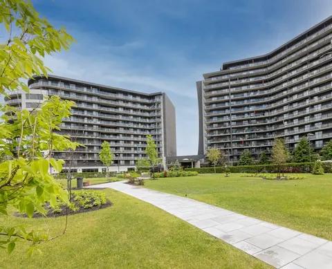 Two high-rise residence buildings beside lawns, trees and a paved path