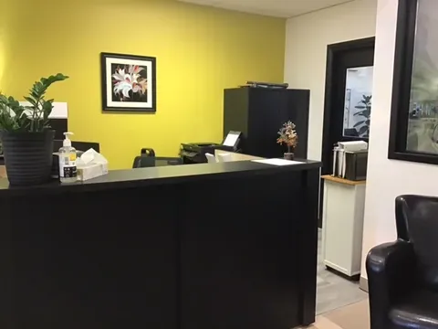 Reception counter beside a yellow wall, cabinets and a potted plant
