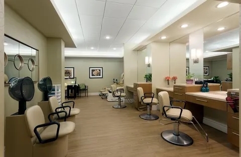 Salon chairs, hair dryers and mirrors in a room with wood flooring