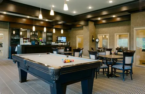 Billiards table beside tables, chairs and a bar counter