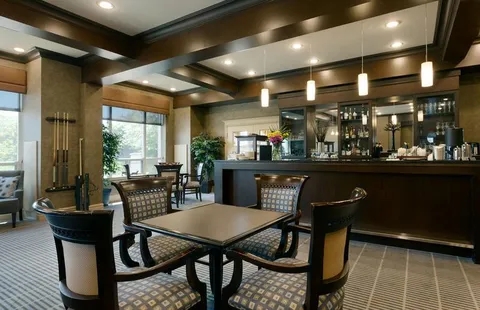 Square table and chairs beside a dark bar counter and large windows