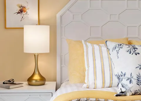 Close view of a bed with floral pillows and a bedside lamp