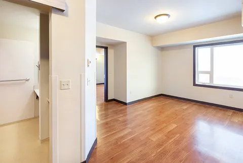 Empty room with wood flooring and a large window beside an open doorway
