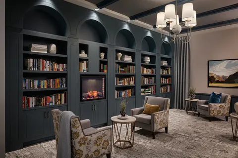 Library with built-in bookcases, armchairs and a fireplace.