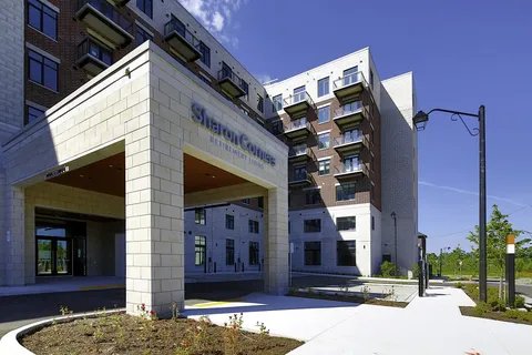 Residence entrance canopy beside a paved walkway and balconies.