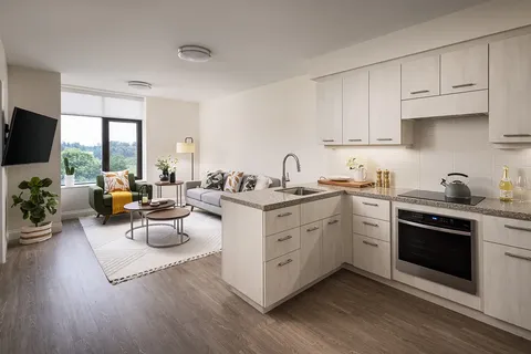 Suite living area beside a white kitchen with an island.