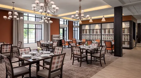 Dining room with set tables, chandeliers and large windows.