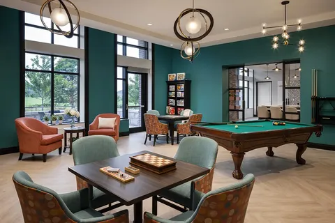 Games room with a billiards table and seating by large windows.