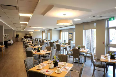 Dining room with set tables beside a row of windows.