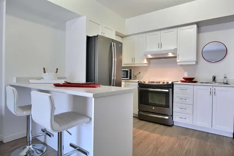 White kitchen with an island, stools and stainless steel appliances.