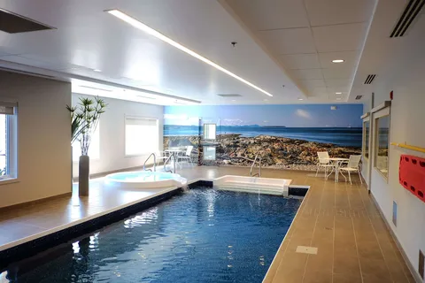 Indoor swimming pool and spa beside a tiled deck.