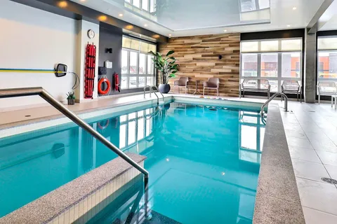 Indoor swimming pool with a tiled surround, large windows and a wood-panelled wall