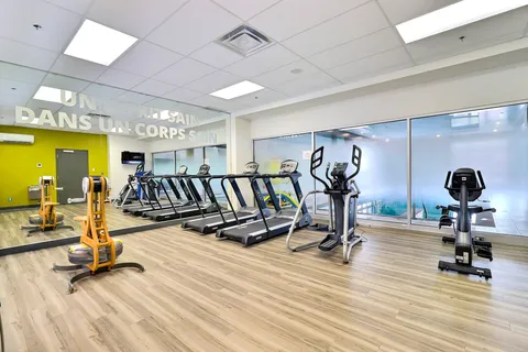 Fitness room with treadmills and exercise equipment beside mirrored walls