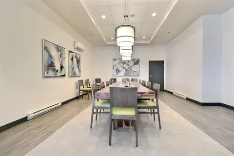 Long dining table with grey chairs beneath pendant lights