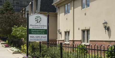 Residence sign, garden beds and windows beside the building.